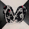 Black pirate-themed fabric accessories with white skull and crossbones print and white rope trim, tied together at the center on a black and white marble surface.